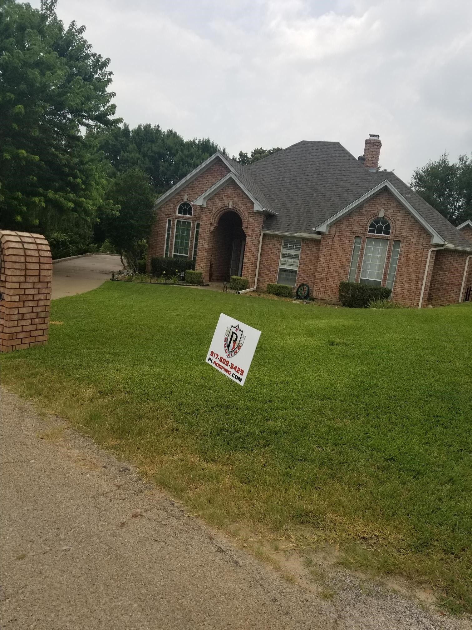 A large brick house with a sign in front of it.