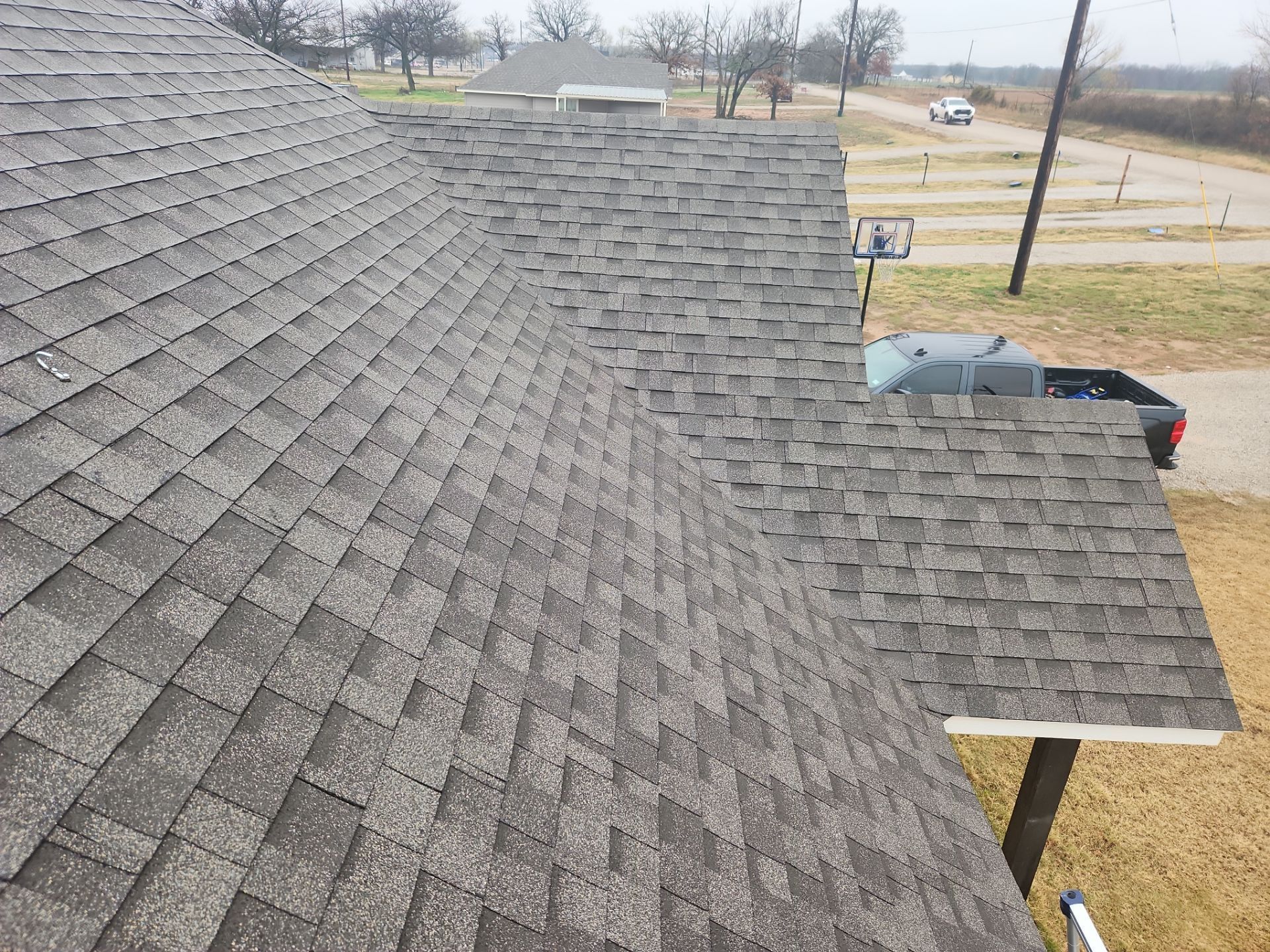 Gray shingle roof of a house on a cloudy day.
