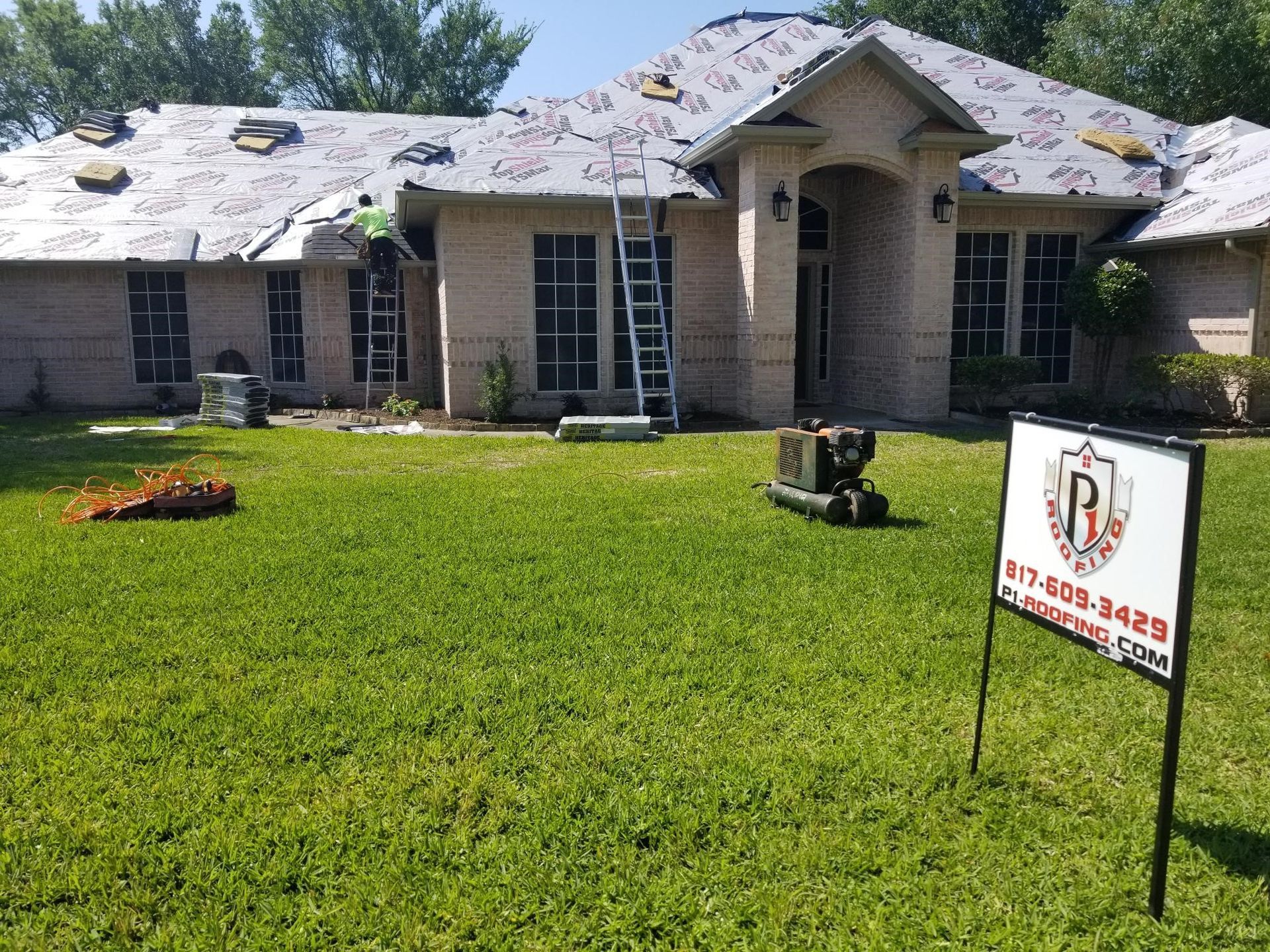 A large house is being remodeled with a sign in front of it.