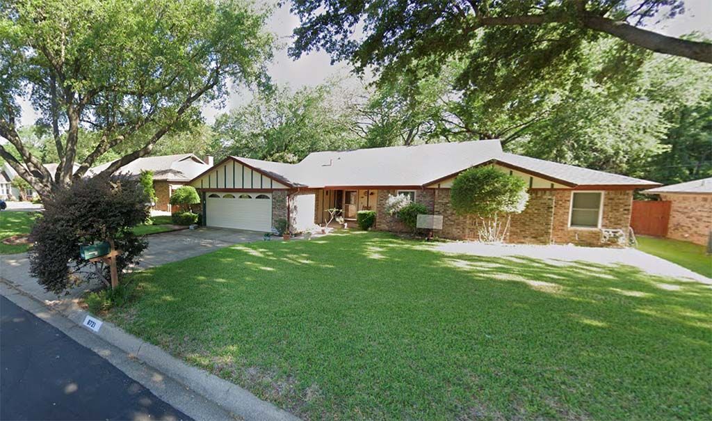 A house with a lot of grass and trees in front of it