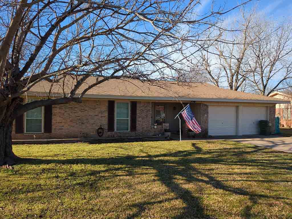 A brick house with a garage and an american flag in front of it.