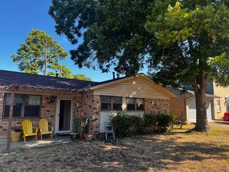 A brick house with a large tree in front of it.