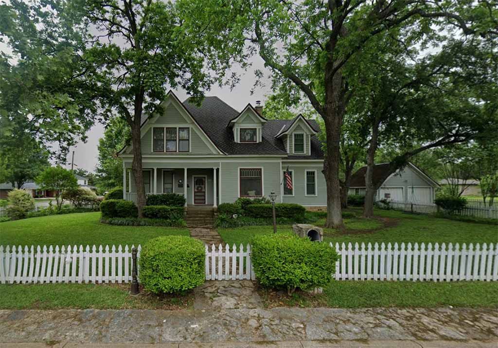 A white house with a white picket fence in front of it