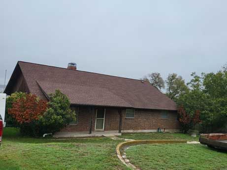 A brick house with a brown roof and a red truck parked in front of it.