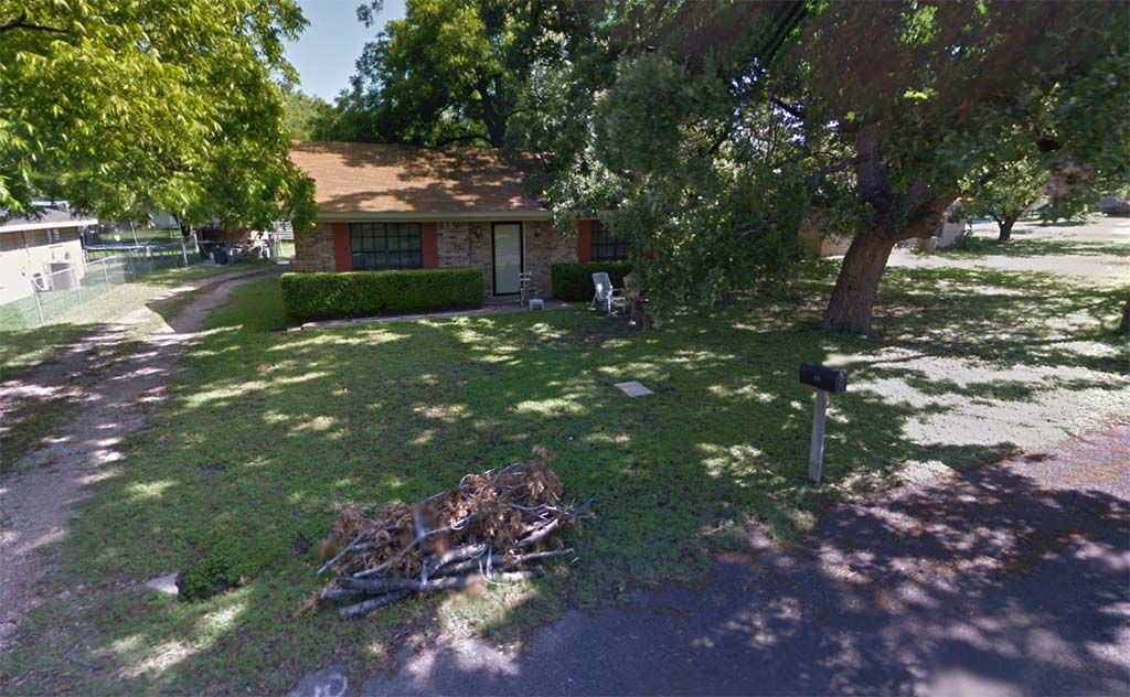 A house with a mailbox in front of it is surrounded by trees and grass.