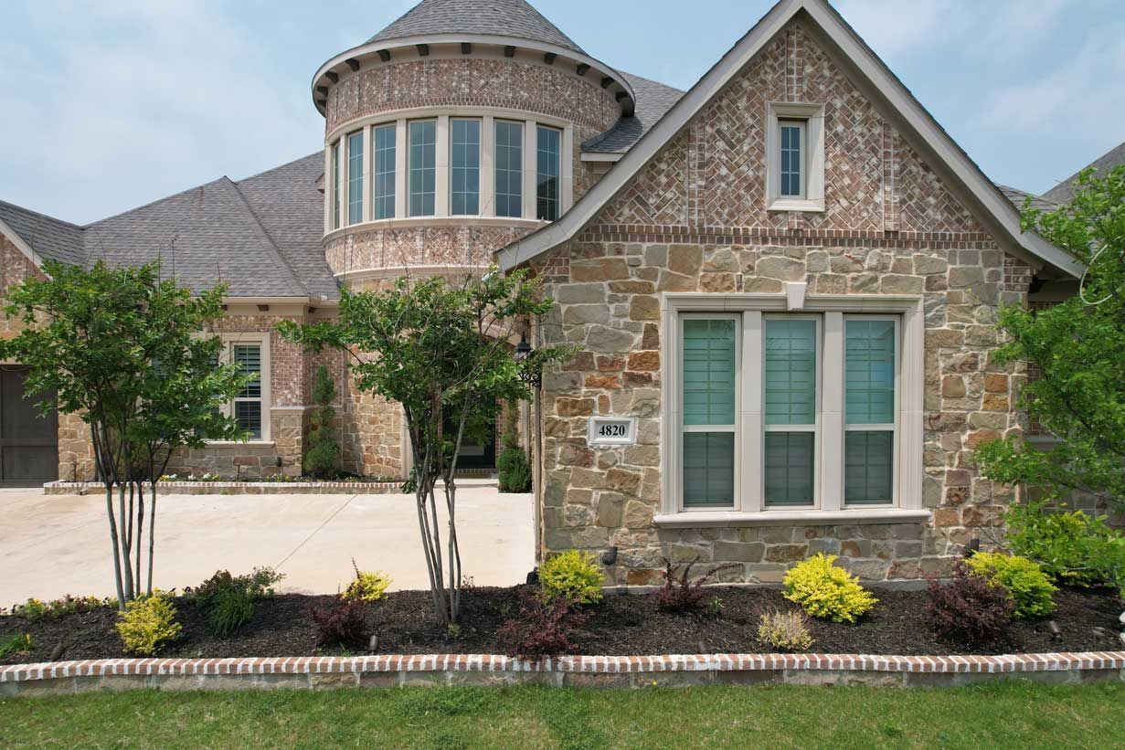 A large stone house with a lot of windows and trees in front of it