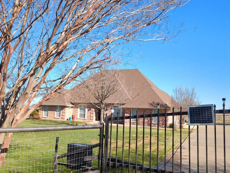 A house is behind a fence with a solar panel on it.
