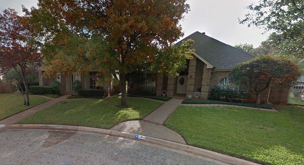 A house with a lush green lawn and trees in front of it