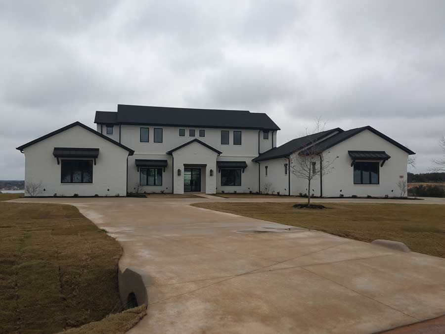 A large white house with a black roof and a driveway