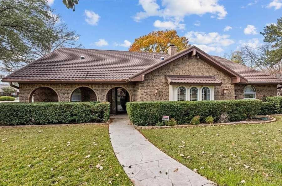 A large brick house with a tile roof and a walkway leading to it.