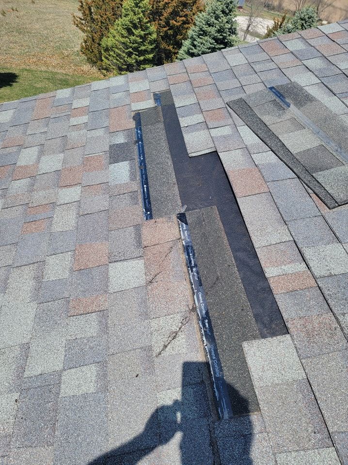 Roof with missing shingles, revealing underlayment. Sunlight, close-up view.