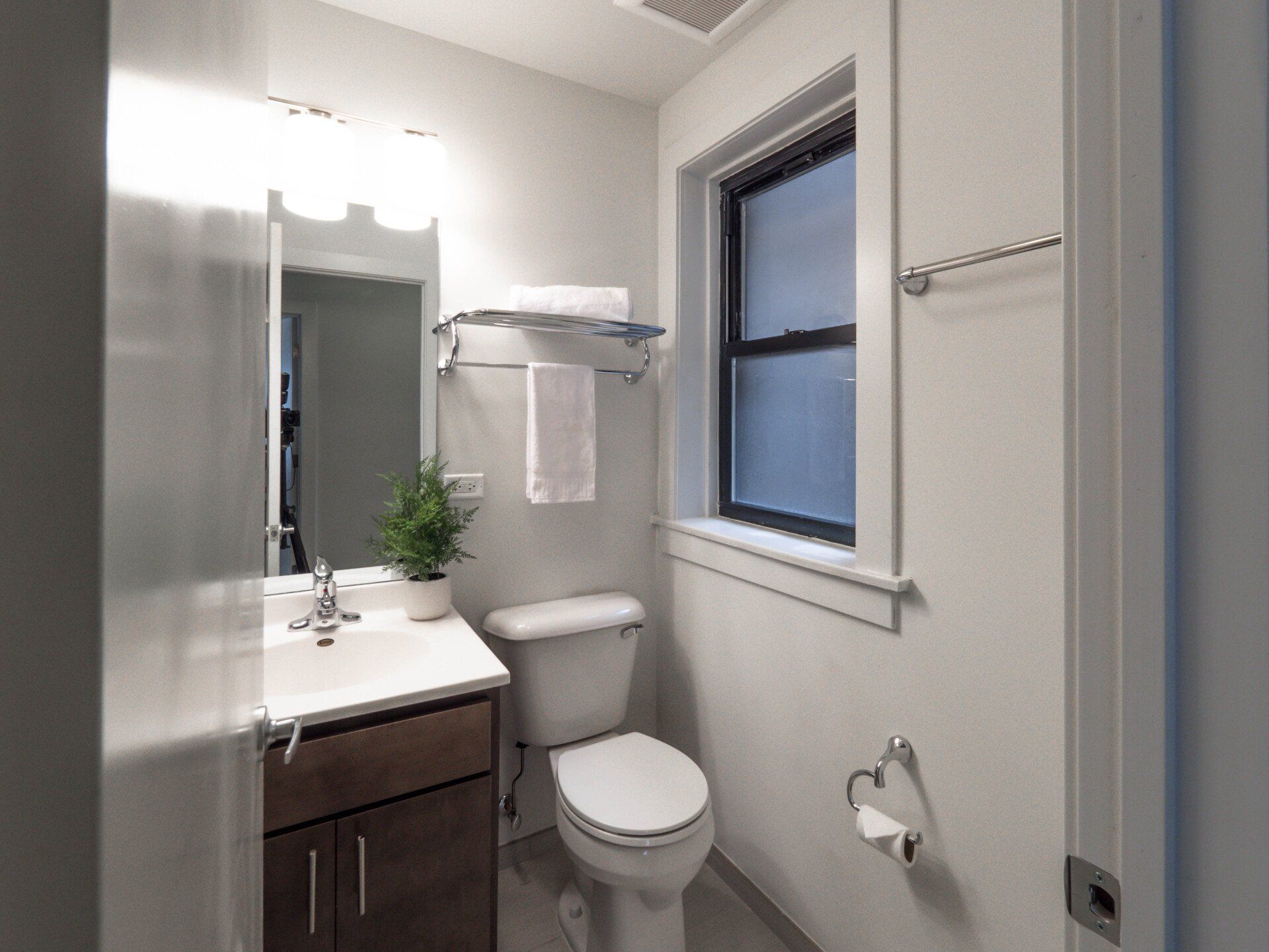 A bathroom with a toilet, sink, mirror, and window at 5425 N Clark Street.