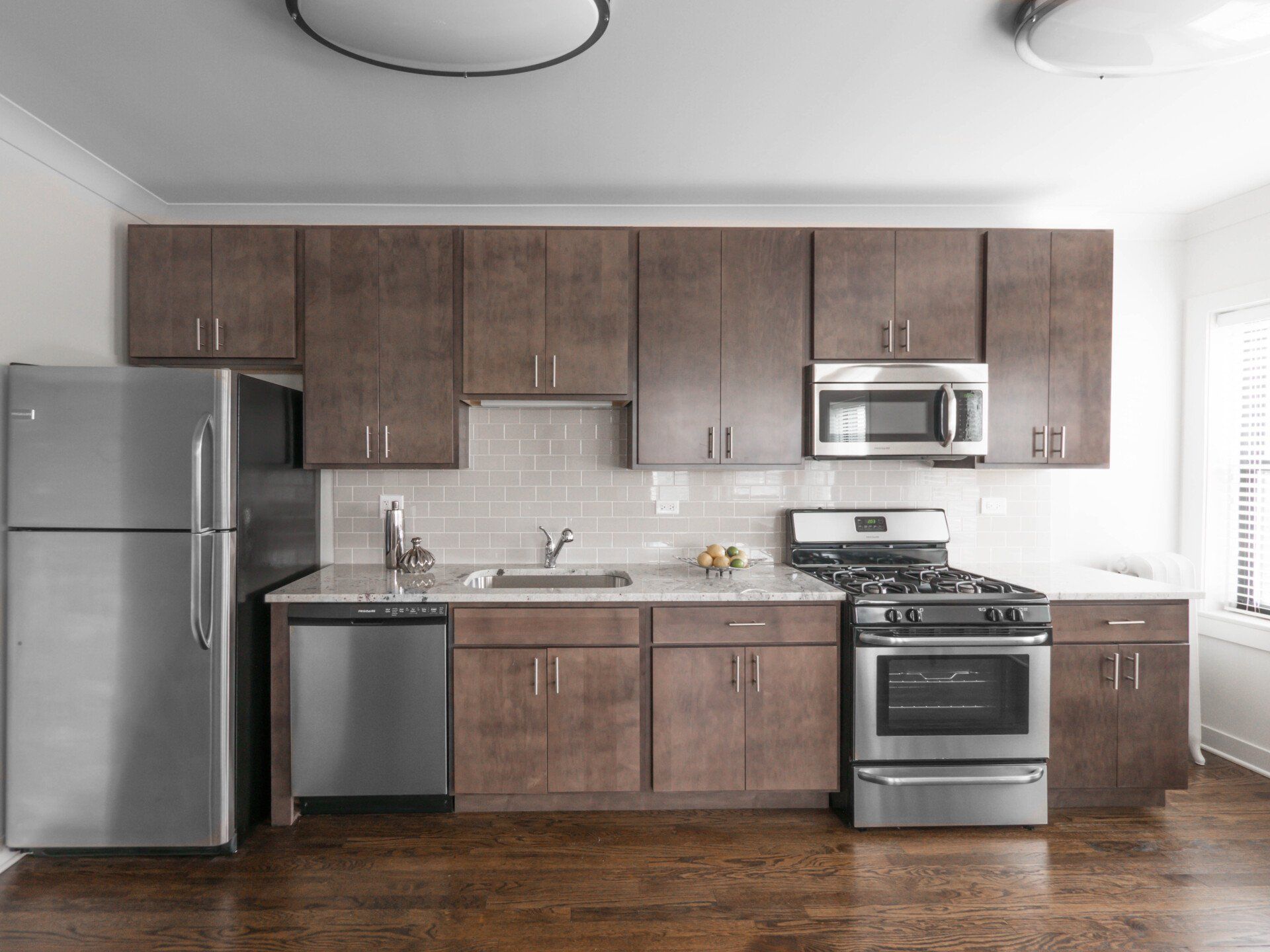 Apartment kitchen with stainless steel appliances and wooden cabinets at 5425 N Clark Street.