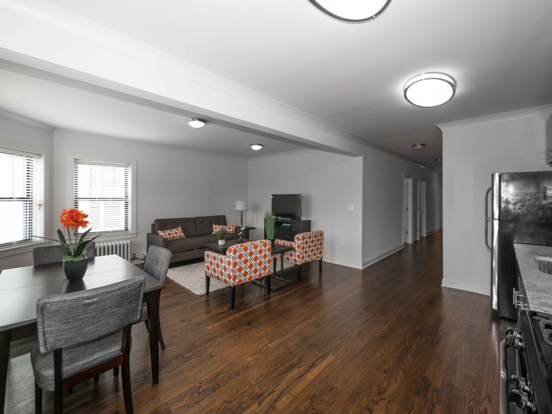 Open apartment floor plan with a couch, chairs, a table, and a refrigerator.
