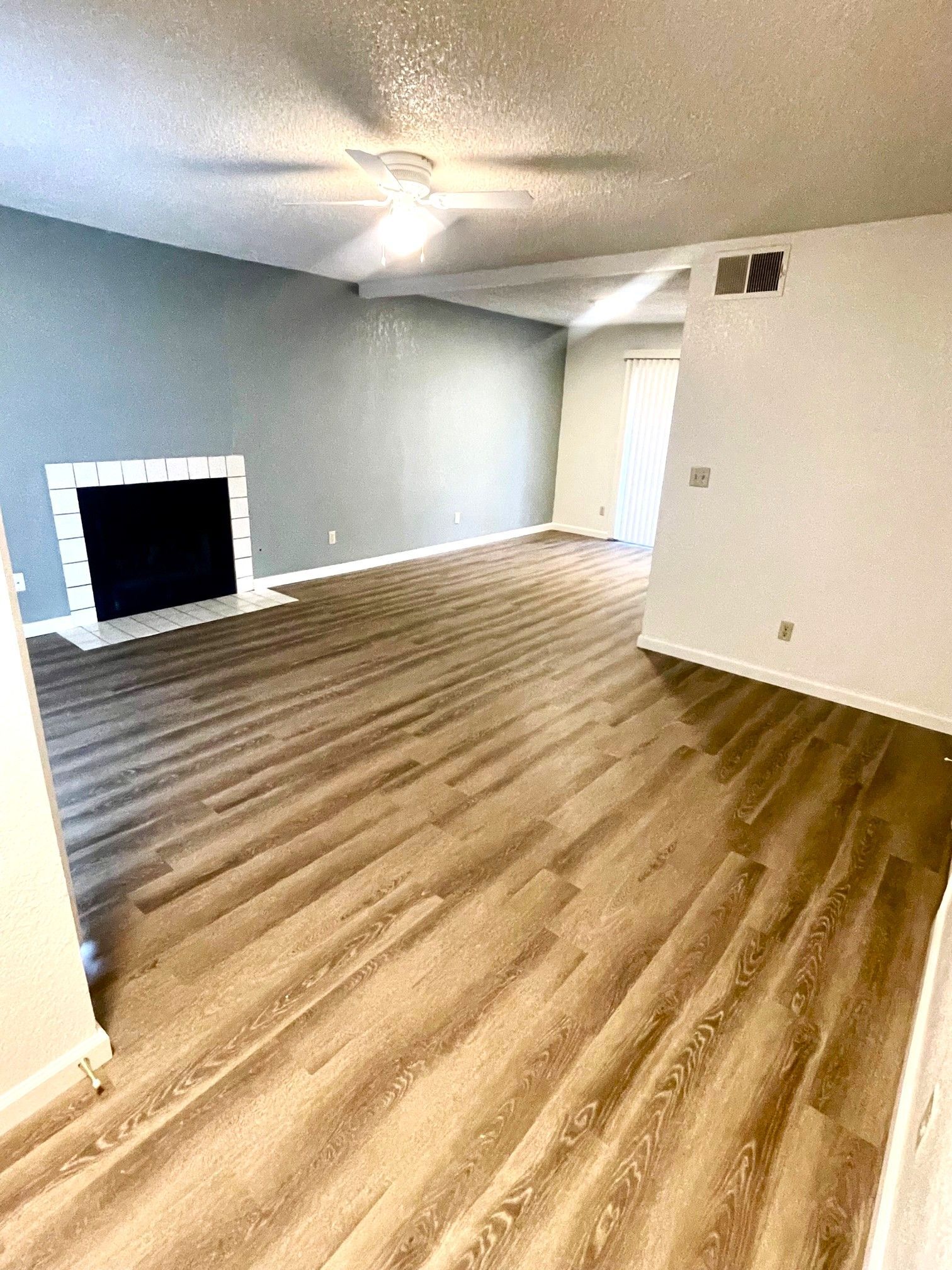 Empty living room with wood-look flooring, a fireplace, and a blue-gray accent wall.
