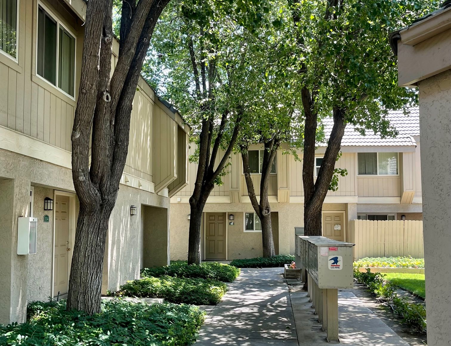 Townhouses with trees and shrubbery; mailboxes on right.