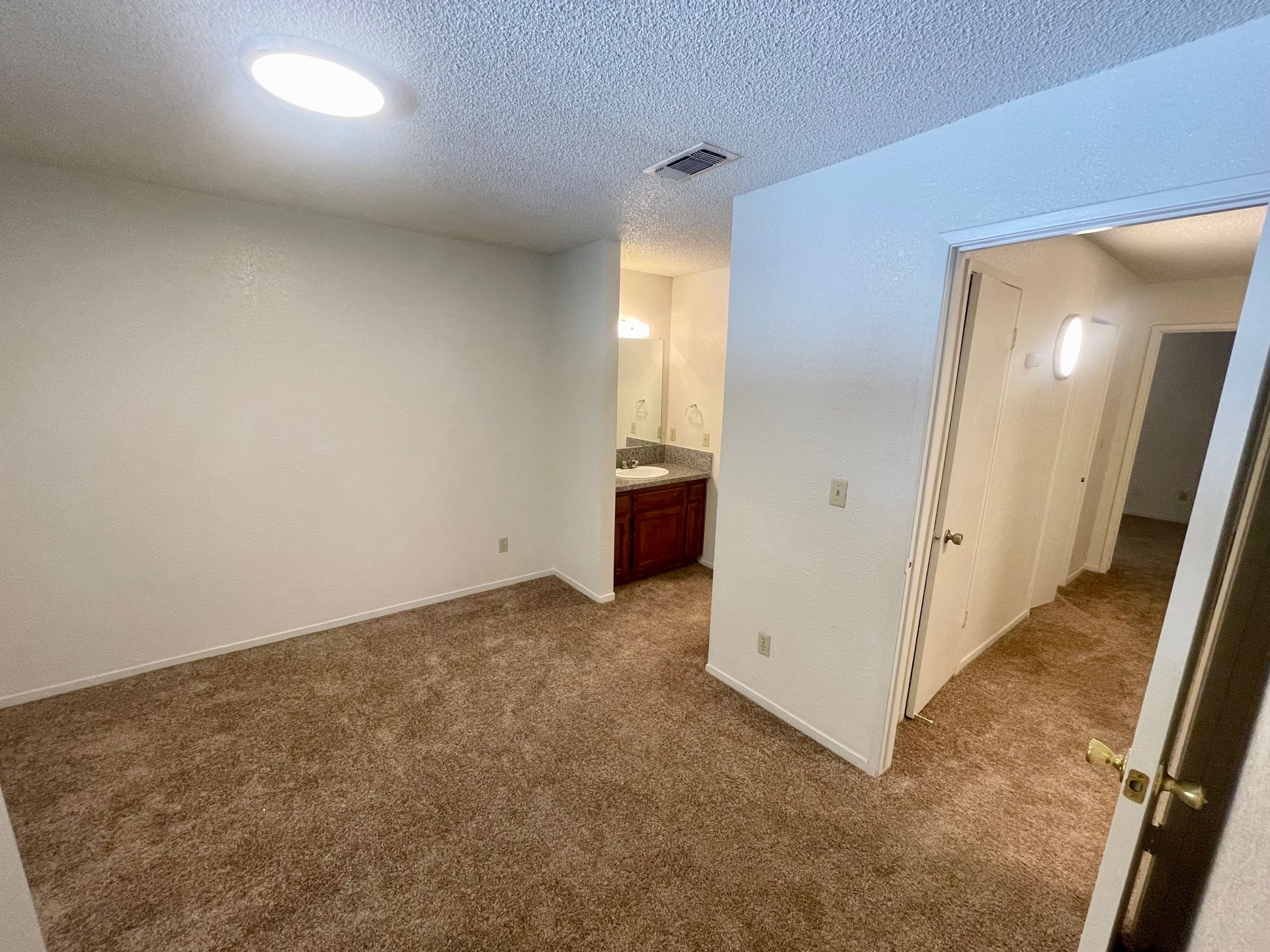 Bedroom with brown carpet, white walls, and doorway to hallway and bathroom.