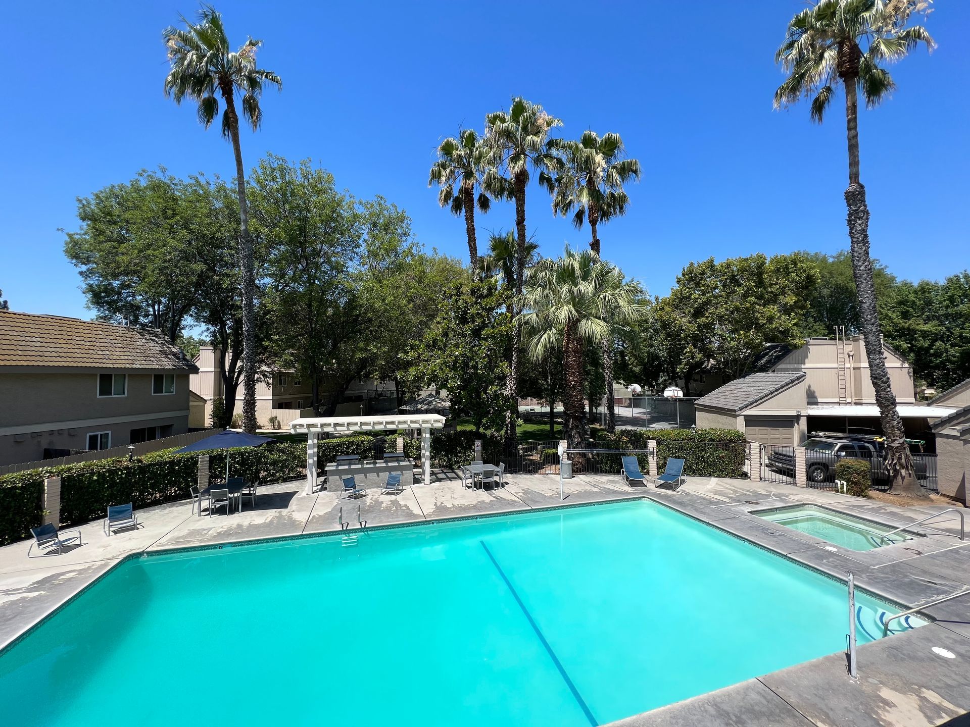 Rectangular pool with blue water, lounge chairs, and apartment building in the background.