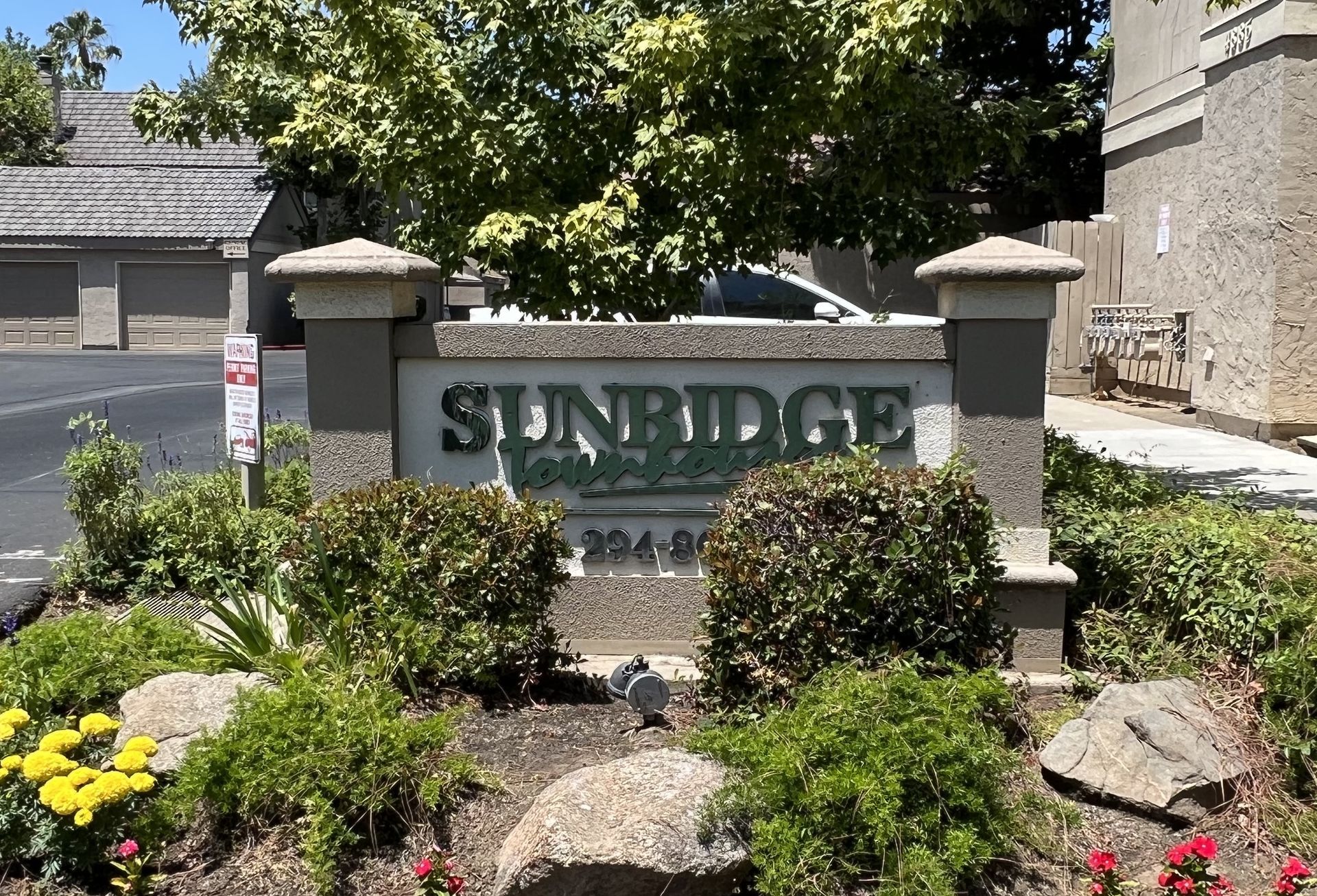 Sign for Sunbridge Apartments, with landscaping and buildings in the background.