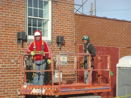 A man in a red jacket is standing on a lift that says aerial