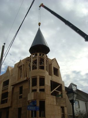 A crane is lifting a tower on top of a building under construction