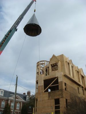 A crane is lifting a large object over a building under construction