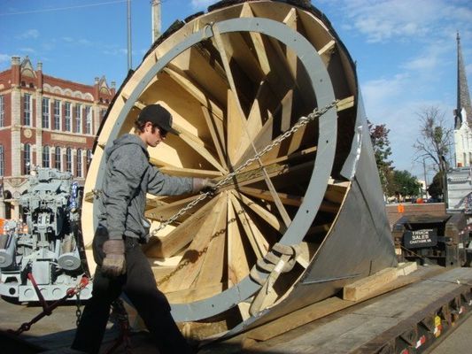 A man is standing next to a large circular object