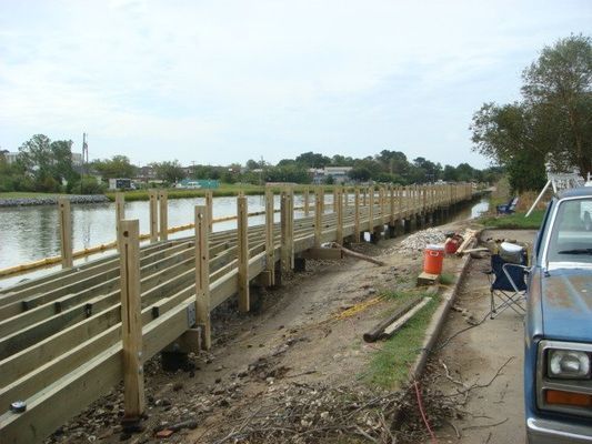 A car is parked next to a wooden bridge over a body of water.