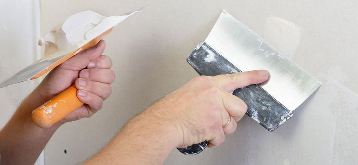 A person is plastering a wall with a spatula.