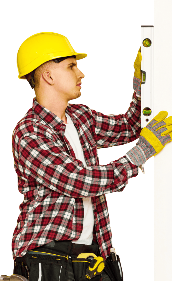 A man in a hard hat is using a level to measure a wall.