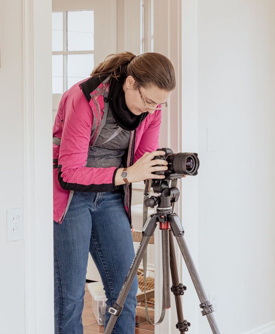 A woman is taking a picture with a camera on a tripod.