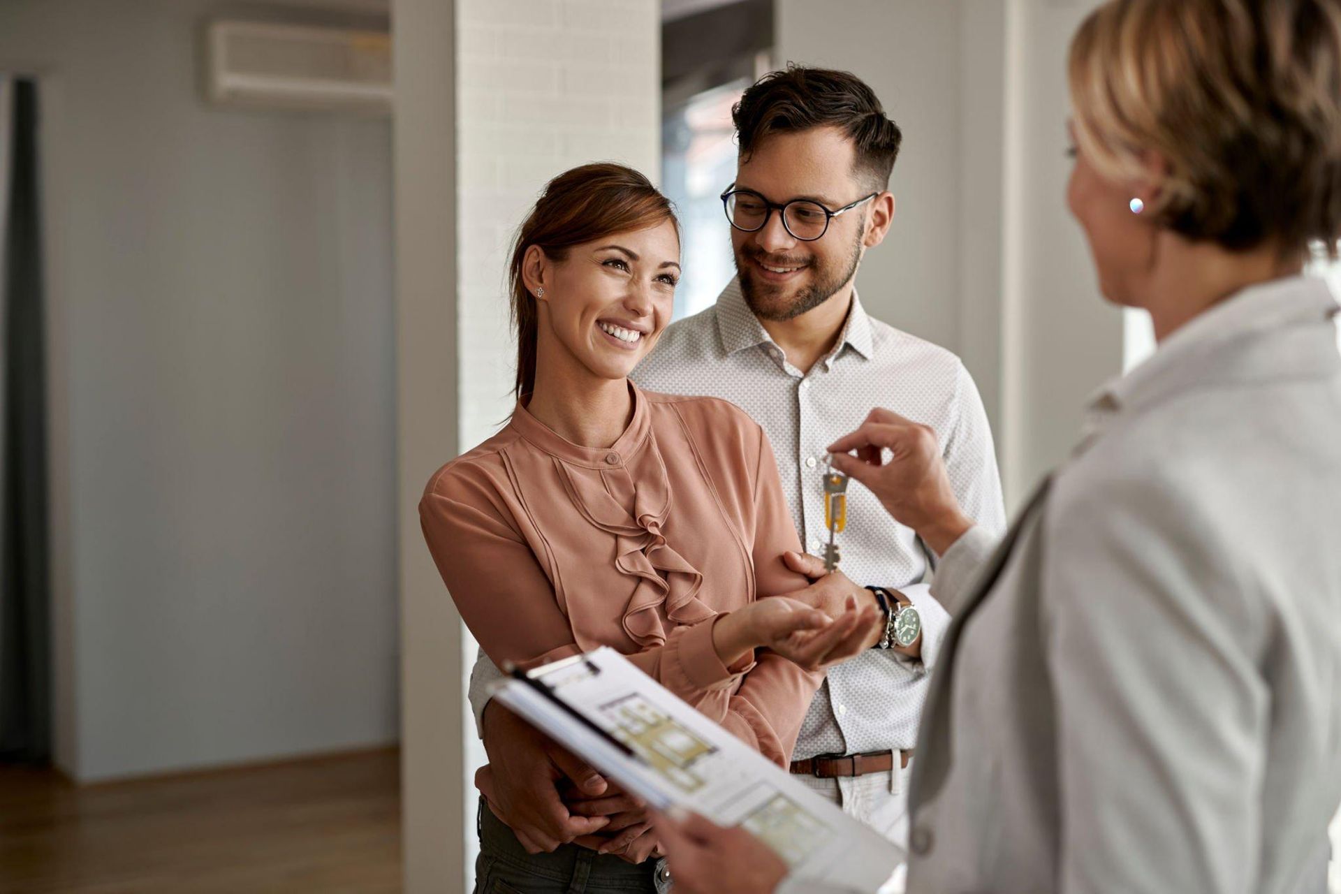 A man and woman are getting keys from a real estate agent.