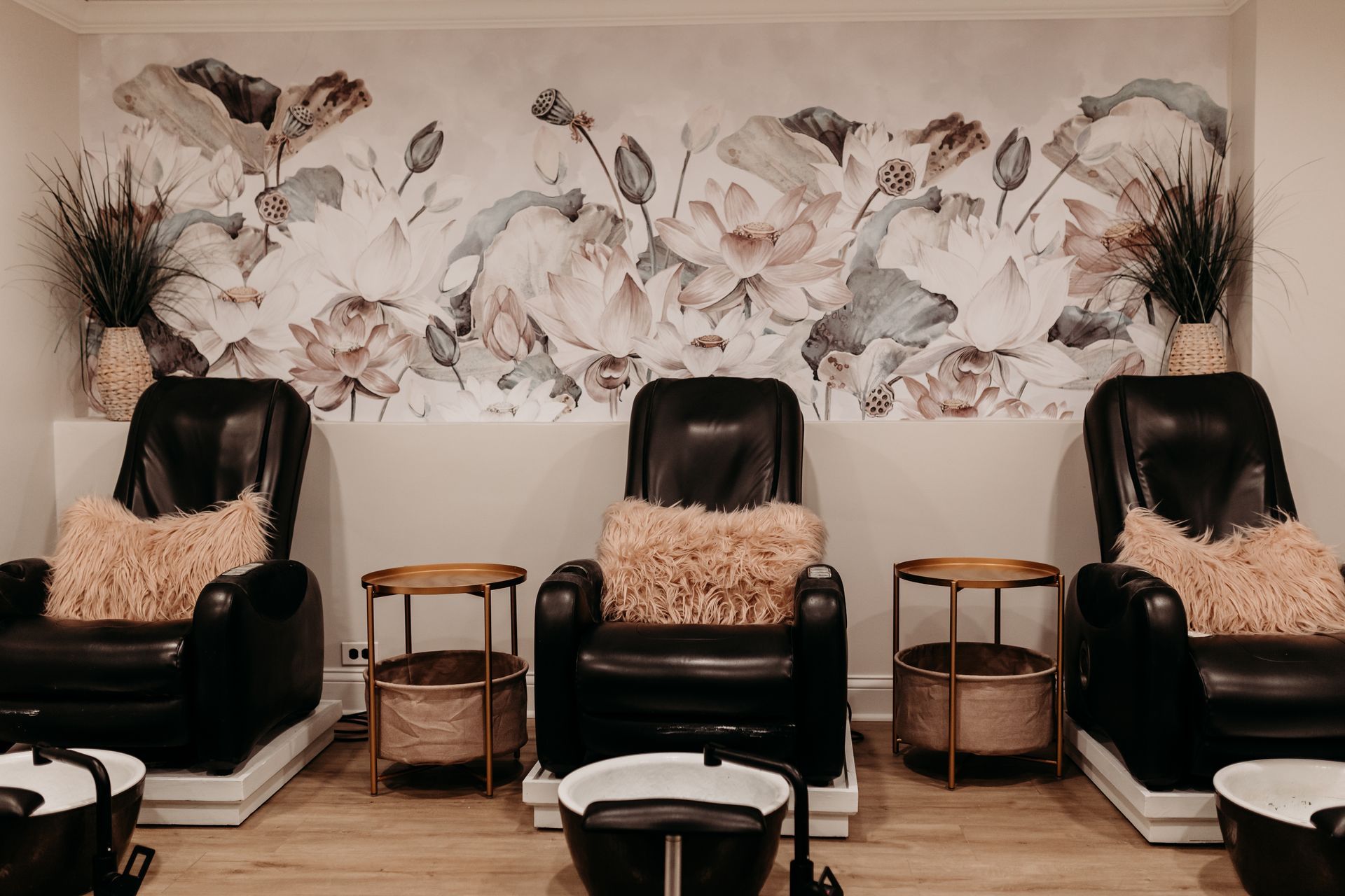 A row of chairs in a salon with a floral wall behind them.