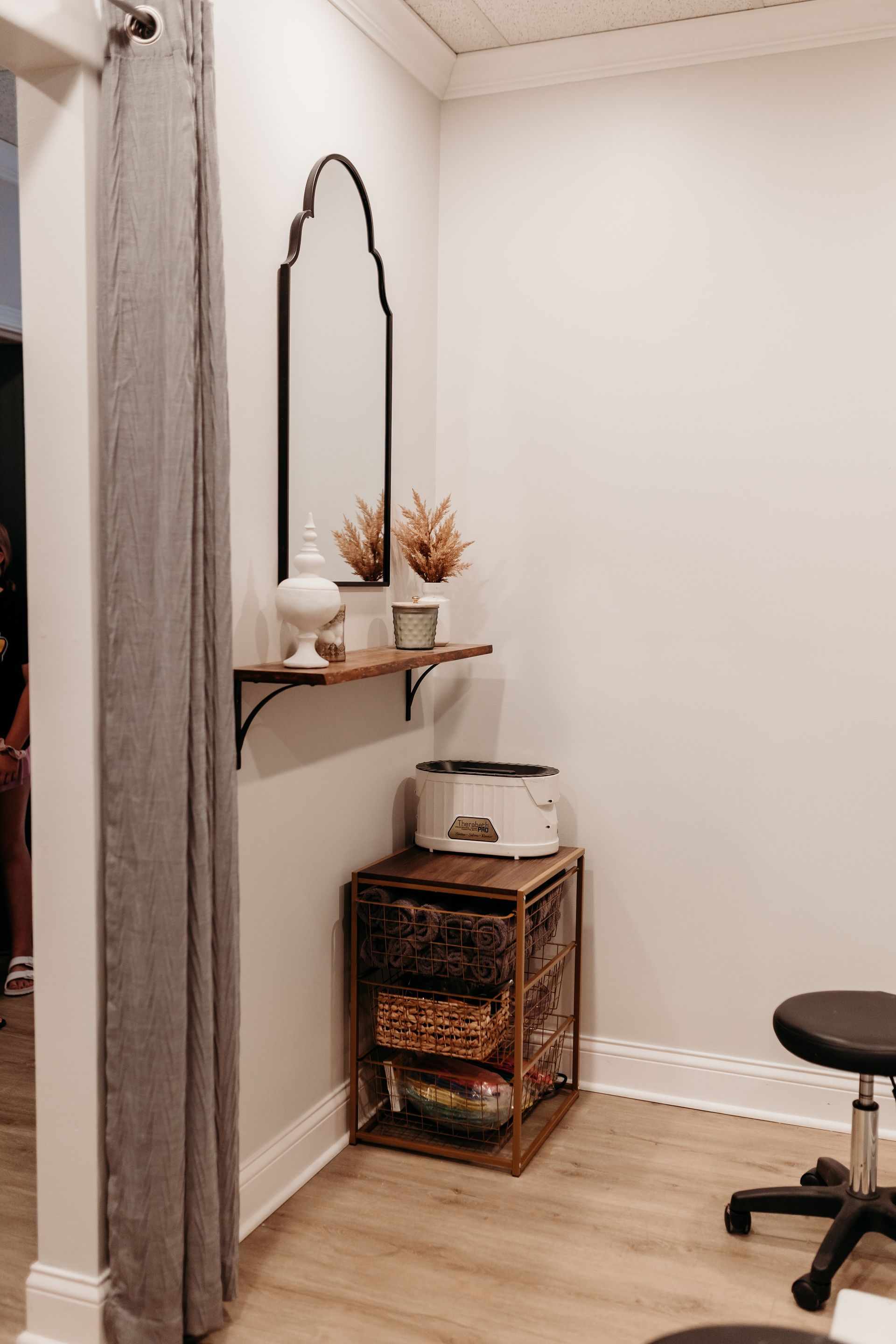 A room with two mirrors , a stool , and a shelf.