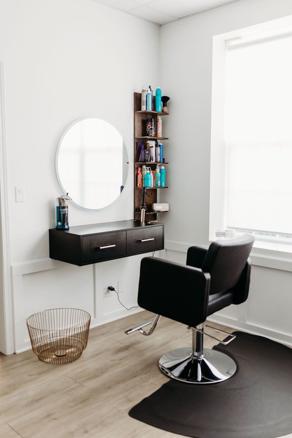 A hair salon with a chair , sink , mirror and shelves.