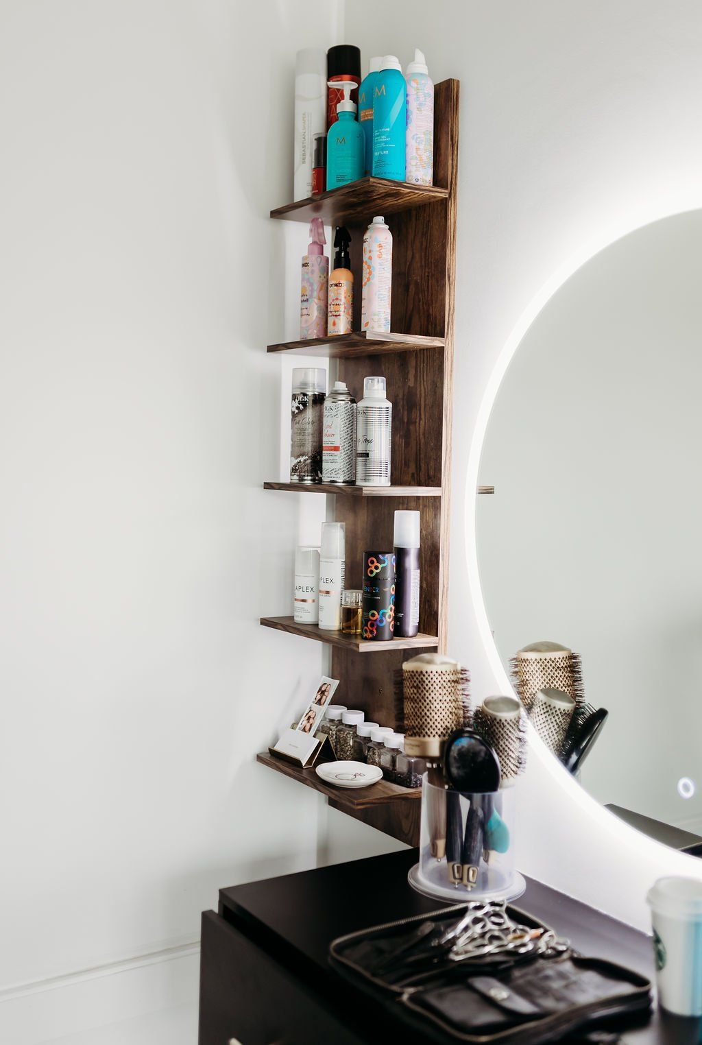 A bathroom with a round mirror and a shelf with bottles on it
