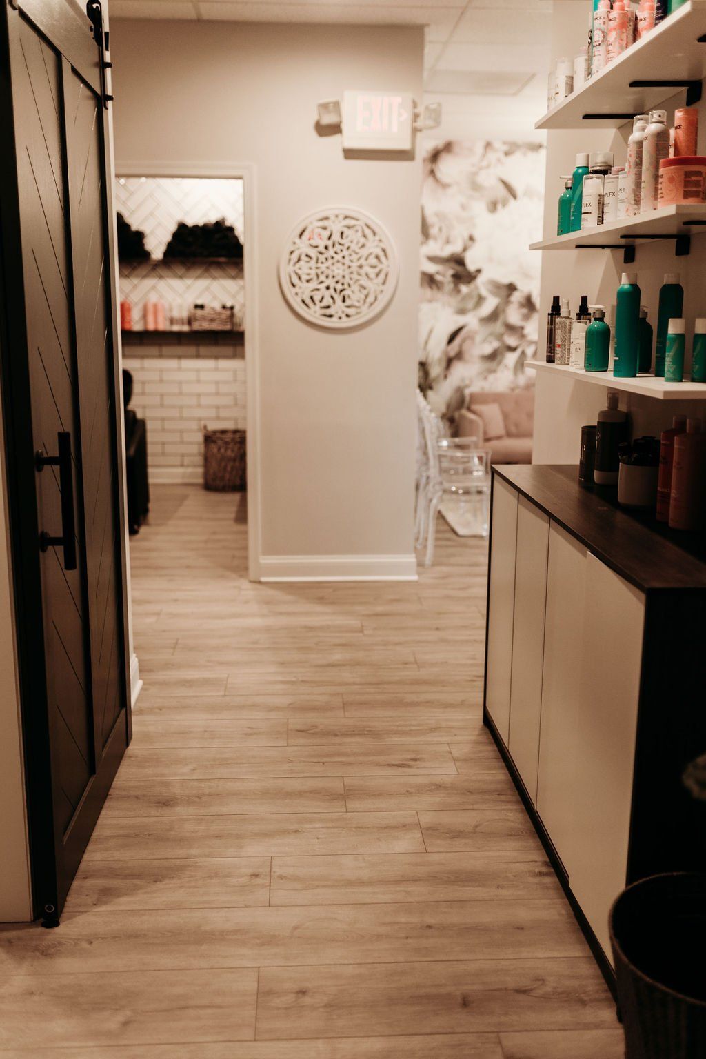 A hallway in a salon with wooden floors and shelves filled with hair products.