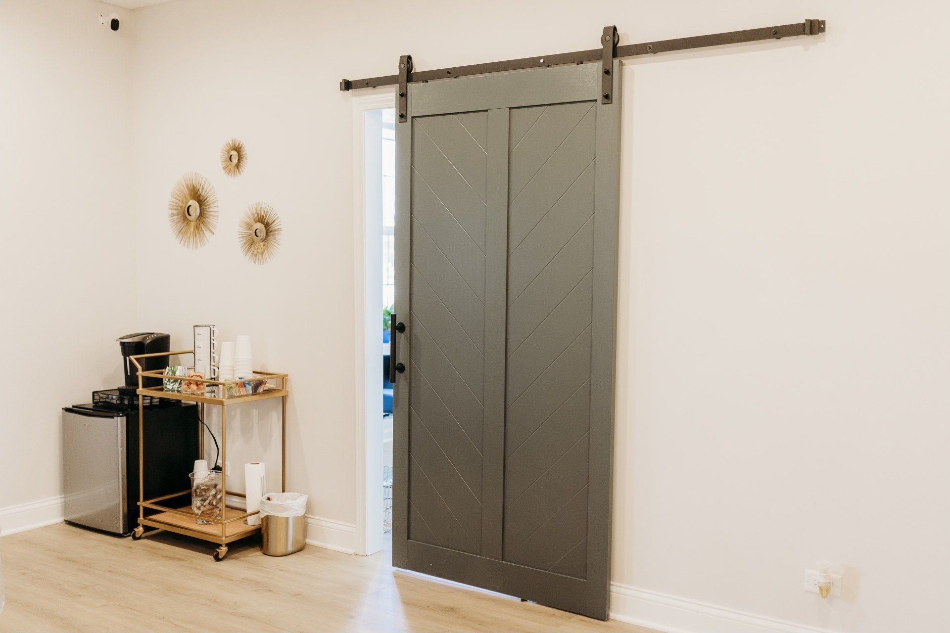 A room with a sliding barn door and a bar cart.