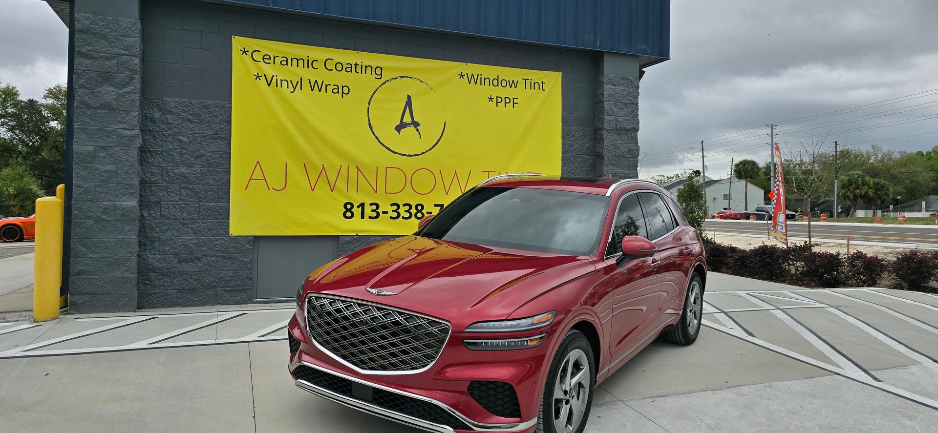 Red SUV parked outside a building with a bright yellow sign and blue wall.