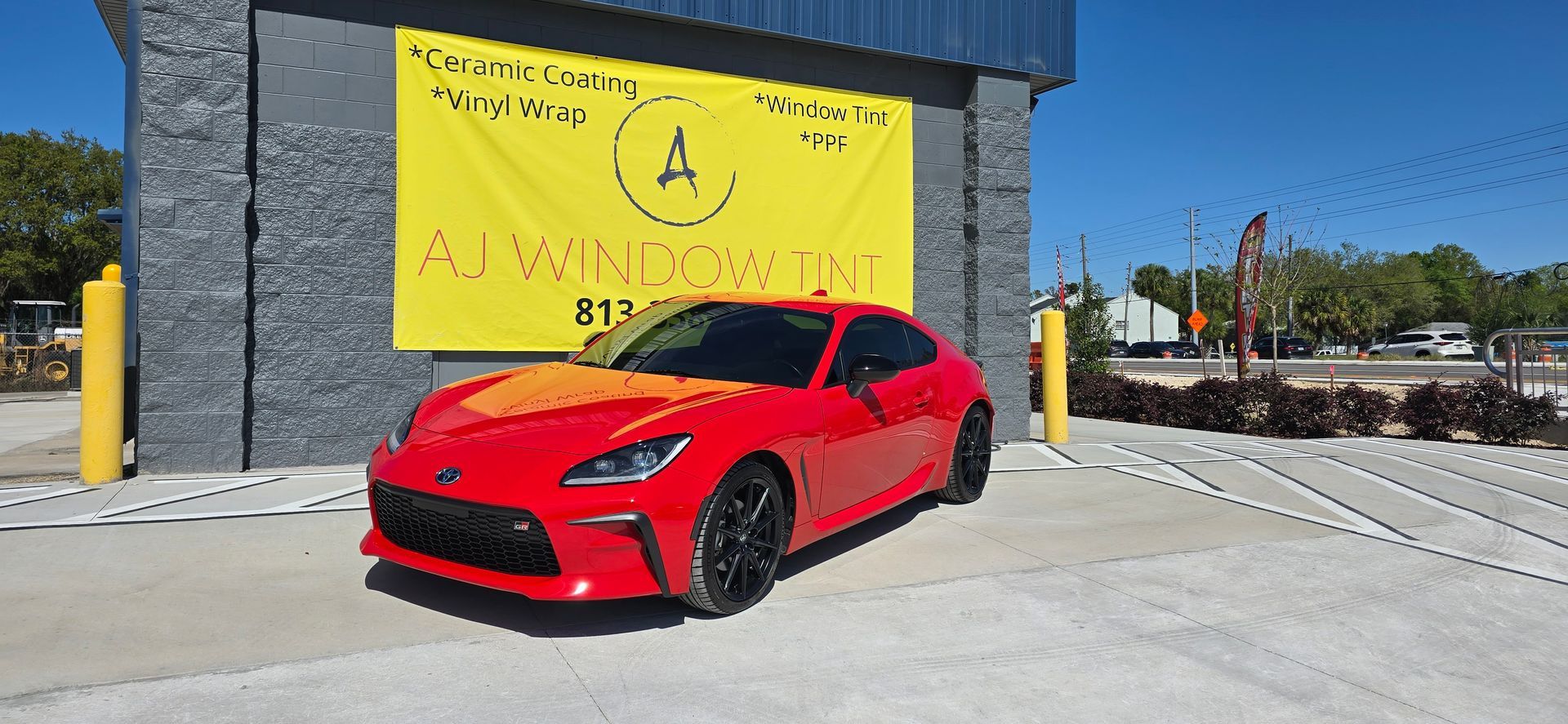 Red sports car parked in front of a building with a large yellow sign.