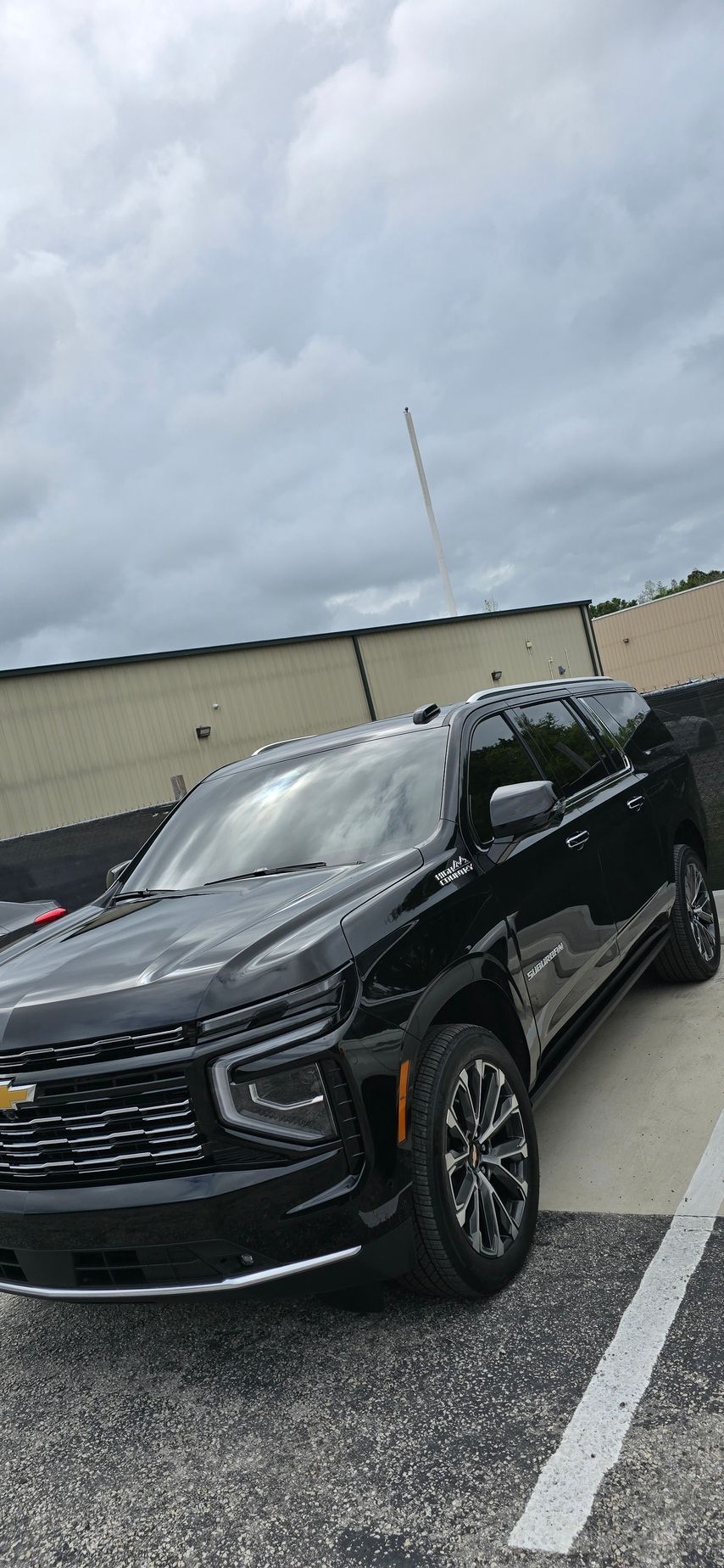 Black Chevrolet SUV parked in a lot under cloudy skies