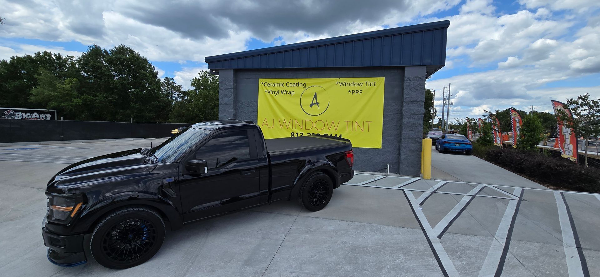 Black pickup truck parked beside a blue building with a yellow garage door.
