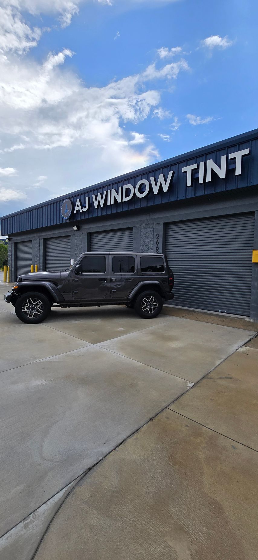 Black Jeep parked outside A1 Window Tint shop on a wet day