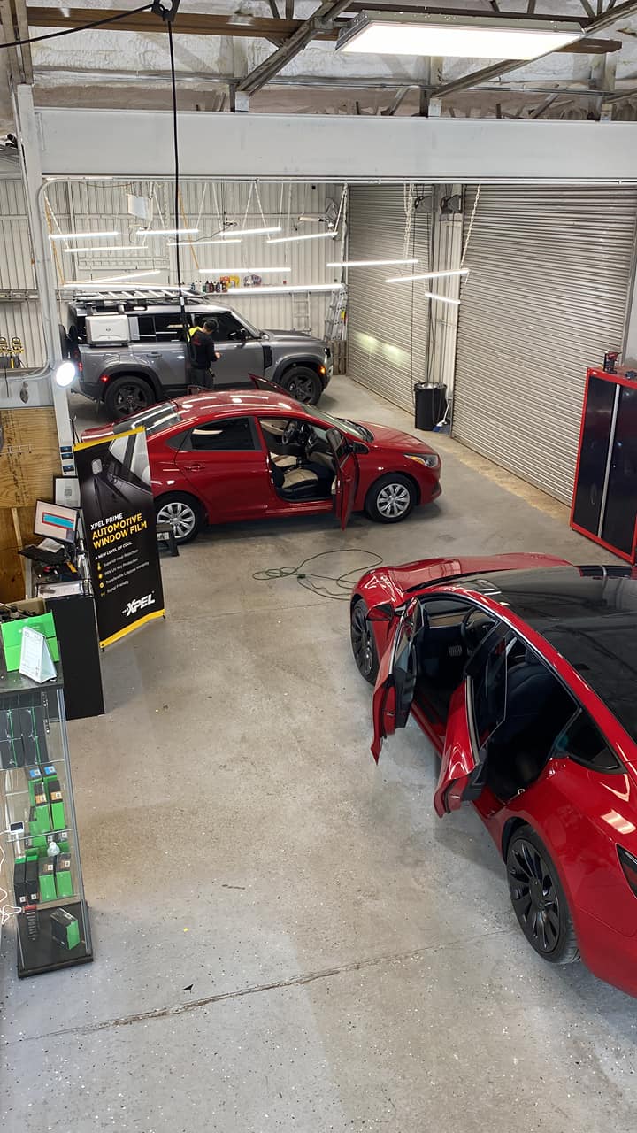 Cars inside a shop, one red car has doors open.