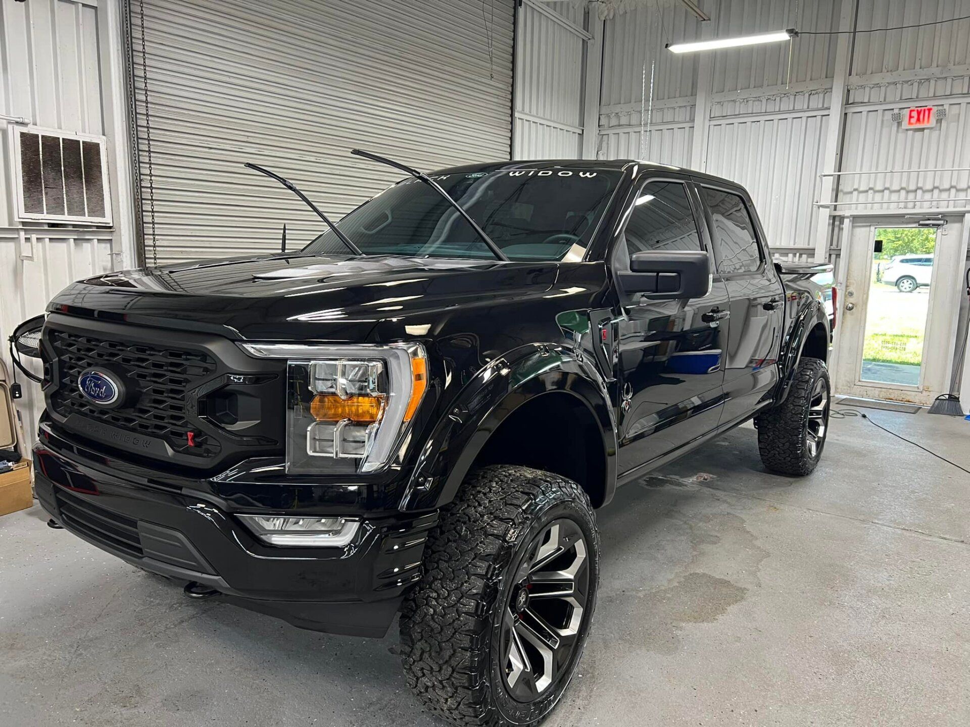 Black Ford truck with large tires inside a garage.