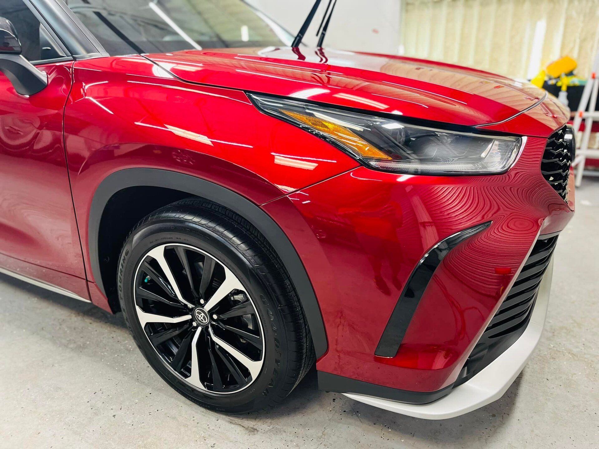 Red SUV, front view, black and silver wheels, white bumper.