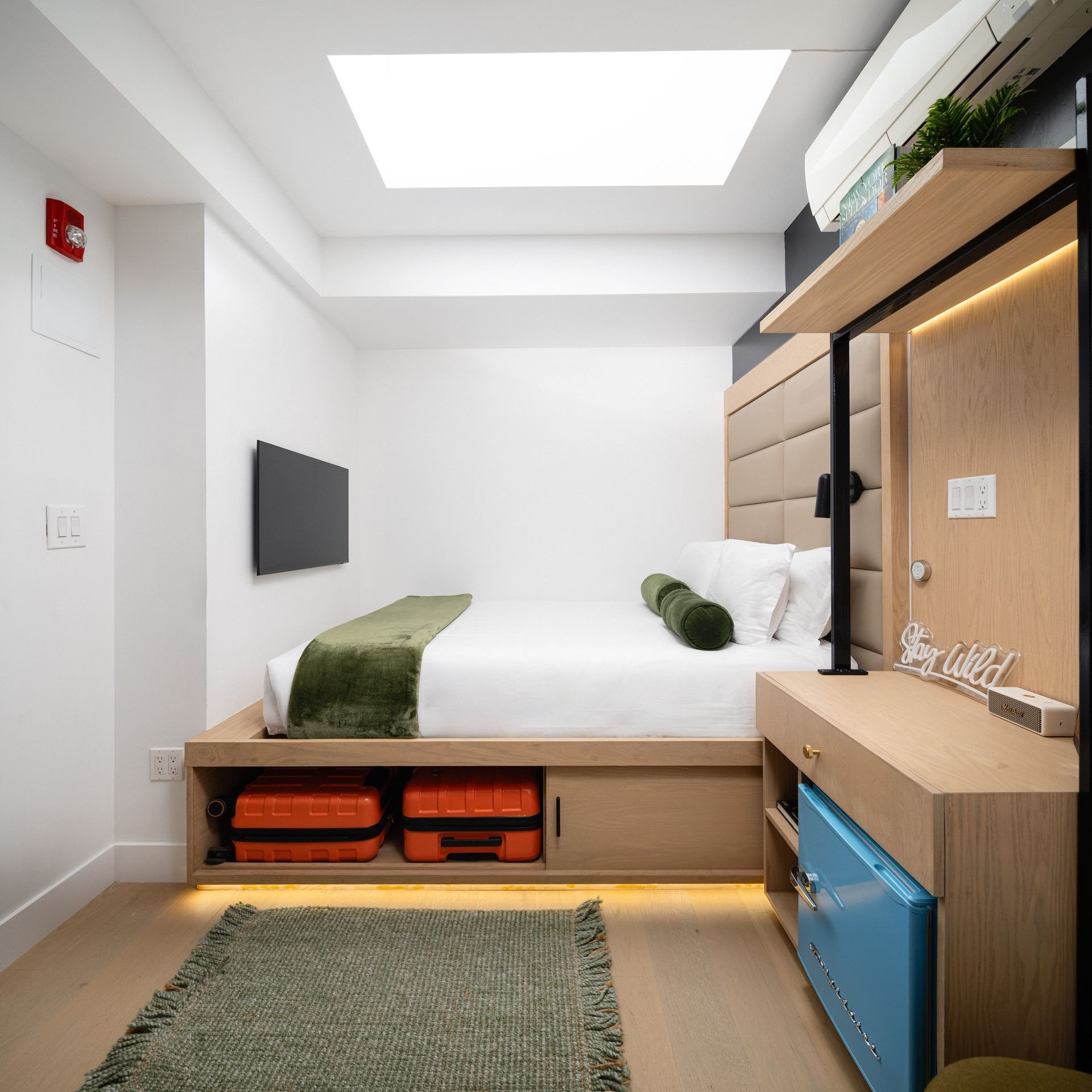 A hotel room with a bed and luggage underneath it