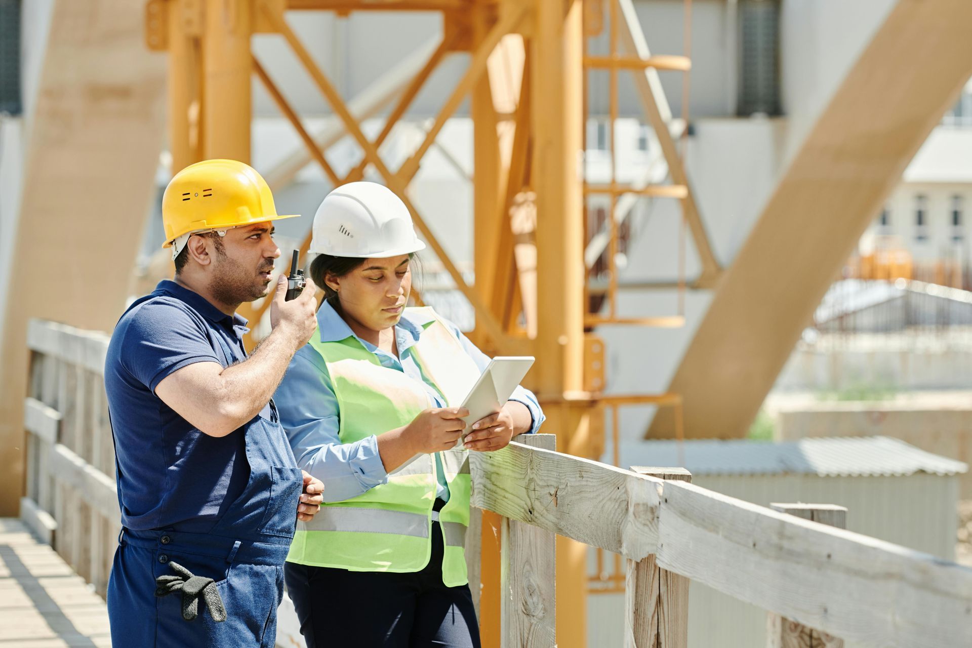 Two construction workers, one with a radio, reviewing inspection