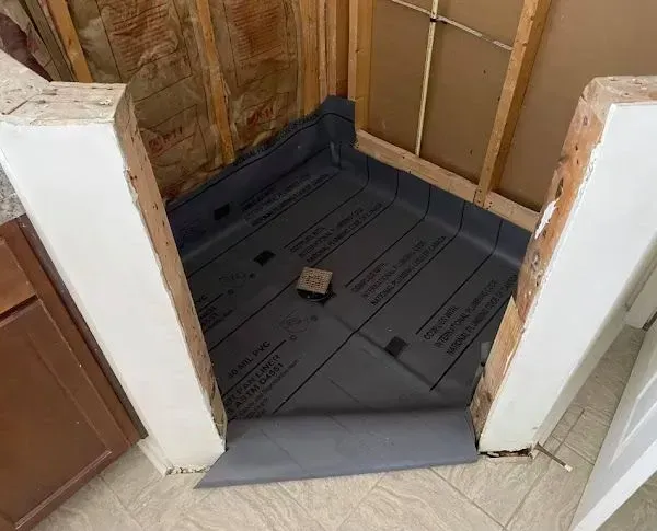 Shower stall under construction; gray waterproof liner installed, framing walls.