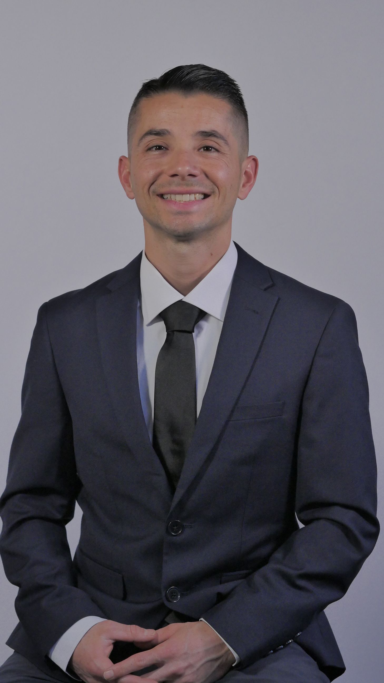 A man with a beard wearing a suit and tie is smiling for the camera.